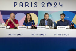 Four people are sitting at a press conference.