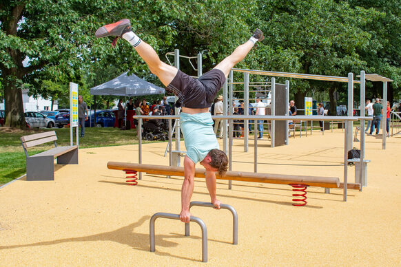 Ein Mann macht einen Handstand auf Fitnessgeräten aus Metall