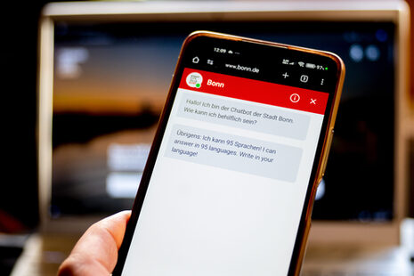 Ein Handy mit dem geöffneten Chatbot der bonn.de Webseite