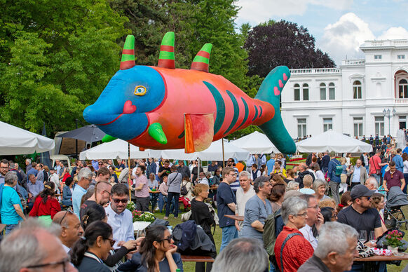 Über den Besuchern im Park der Villa Hammerschmidt schwebt ein riesiger Fisch