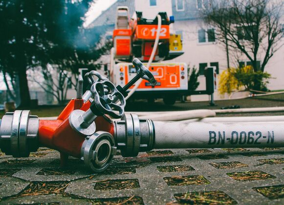 Feuerwehrfahrzeug und Wasseschlauch an Hydrant.