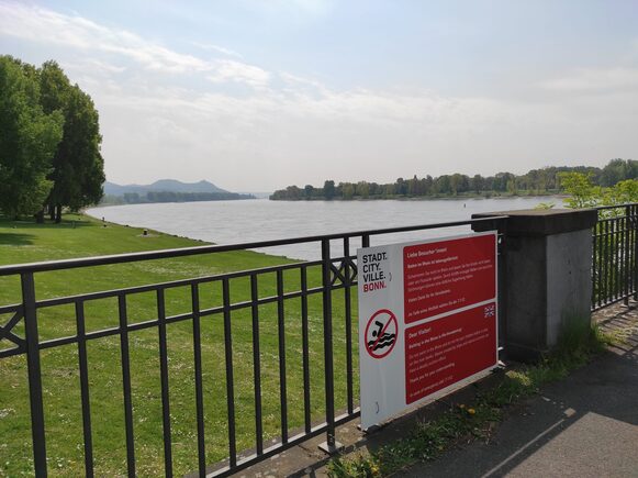 Warnschilder am Rhein weisen in Deutsch und Englisch auf die Gefahren von Baden im Rhein hin
