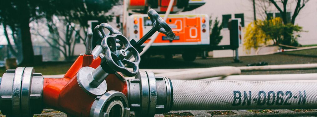 Feuerwehrfahrzeug und Wasseschlauch an Hydrant.