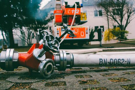 Feuerwehrfahrzeug und Wasseschlauch an Hydrant.