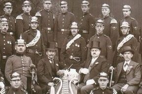 Die Schwarz-weiß-Aufnahme zeigt eine Gruppe von 26 Männern des Löschzugs Dransdorf im Jahr 1925, die meisten davon in Uniform und zeitgenössischen Helmen.
