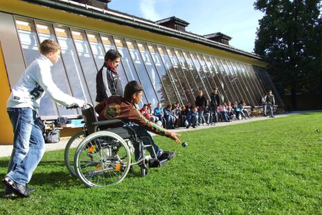 Un ragazzo in sedia a rotelle gioca a bocce con altri bambini